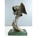 A bronze figure of an owl on a tree branch, raised on a green marble base.