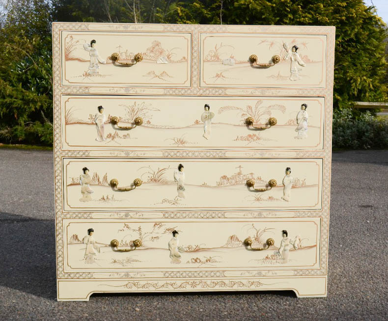 A Chinese white lacquered chest of drawers with mother of pearl figures and gilded highlights.