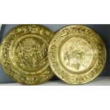 A pair of brass relief decorated chargers.