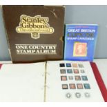 A stamp album containing a penny black and Stanley Gibbons reference book.