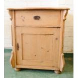An antique pine cupboard with shaped top and single drawer.