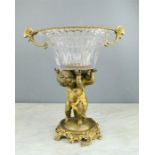 A brass and cut glass comport, modelled with three cherubs,