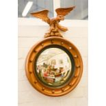 A giltwood 'porthole' wall mirror with eagle surmount.