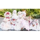 A group of bears dressed in dolls clothing.