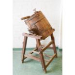 An antique butter churn barrel on stand.