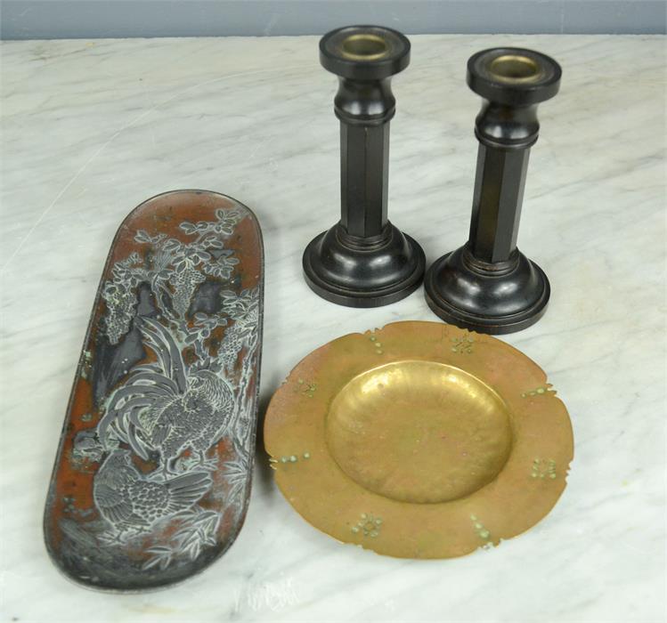 A copper and pewter pin dish depicting cockerels, a pair of ebonised candle sticks, and a brass