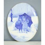 A Doulton Burslem oval blue and white plaque depicting children in the snow, 24 by 19cm.