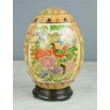A ceramic Chinese egg on stand, painted with birds and peonies.