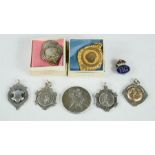 A group of silver fobs, a silver gilt fob and a badge.