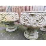 Two garden urns on plinths.