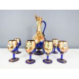 A French blue glass and gilded set of wine jug and six wine glasses, modelled with flowers.