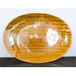 A large slipware glazed terracotta oval dish.