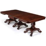 A fine Georgian mahogany triple pedestal dining table, with boldly carved lion paw feet, raised on