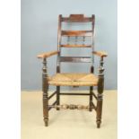 A 19th century armchair, rush seat, bobbin turned front rail and shaped ladder back.