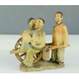 A stoneware Japanese figure group, three figures and a cart with nodding heads, painted with