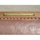 An oak chair upholstered in leather with leather arms, bearing brass engraved plaque.