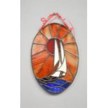 A stained glass oval panel depicting a boat.