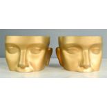 A pair of modelled head sections, painted gold.