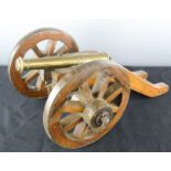 An antique brass and wooden model cannon.