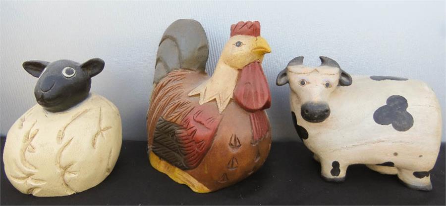 A wooden carved and painted model cow, chicken and sheep.