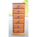A pine chest of drawers with blue glass handles.