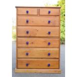 A pine chest of drawers with blue glass handles; two over five long drawers.