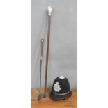 A riding crop, walking cane with owl handle, and a policeman's helmet.