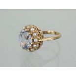A 9ct gold ring with blue oval cut stone and seed pearl border, 5.7g total.