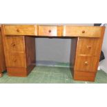 A 1930s walnut veneered desk with glass top, shaped front, and a series of drawers.