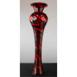 A tall red and black 1950s glass vase, with swirl decoration.