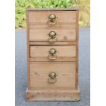 An antique pine chest of drawers with brass cup handles.