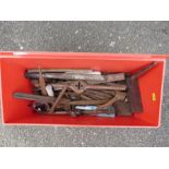 A red box containing tools; chisels, planes, etc.