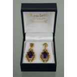 A pair of yellow metal and amethyst earrings, the scrollwork setting with central pear cut