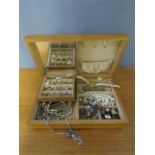 A jewellery box containing earrings, necklaces, watches, coins and other jewellery.