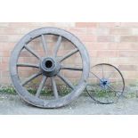 An antique cart wheel, and a small iron wheel.