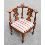An Italian walnut carved corner chair, with carved cherub head to the top rail, upholstered seat.