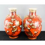 A pair of late 19th/early 20th century Japanese vases, the ovoid bodies with red ground and raised
