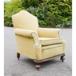 A Victorian armchair, upholstered in yellow velvet with green piping, with mahogany turned feet