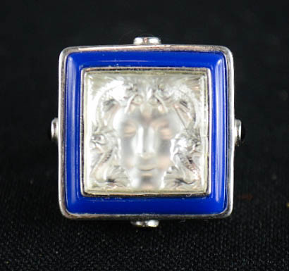 A Lalique Art Deco silver and crystal Masque Du Femme ring, bordered by blue enamel piping with