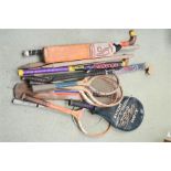 A group of hockey sticks, badminton rackets and tennis rackets.