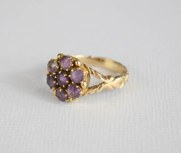 A yellow metal and amethyst cluster flower head ring.