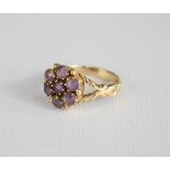 A yellow metal and amethyst cluster flower head ring.