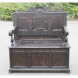 An oak 17th century style box settle, with carved back, and triple panel front.