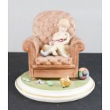 A figure of a young girl seated in an armchair with a spinning wheel. 17cm high.