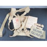 A selection of Home Guard manuals, insignia, belt slider and webbing straps.