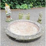 A group of stone garden ornaments; bird bath top, gnome, castle.