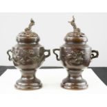 A pair of bronze Chinese urns and covers, with dog of fo finials.