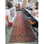 A large red ground Persian runner 5 metres by 1 metre approximately. , together with a further rug.