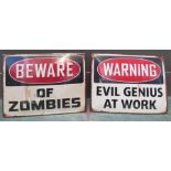 Two metal signs; Beware of the Zombies and Evil Genius at Work.