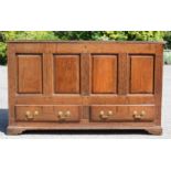 An 18th century oak mule chest, the front having four fielded panels above two drawers with brass